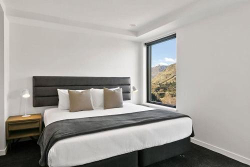 a bedroom with a large bed with a large window at Rihir Apartment at the base of Coronet Peak in Queenstown