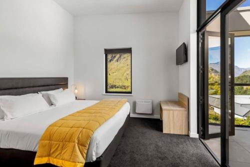 a bedroom with a large bed and a balcony at Riverview Penthouse - Apartment 19 in Queenstown