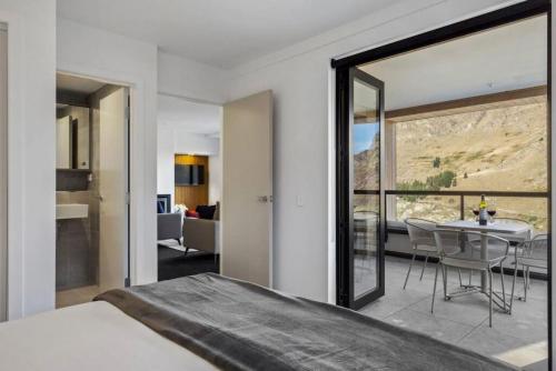 a bedroom with a large window and a table with chairs at Residence Du Parc - Awa Apt 16a in Queenstown
