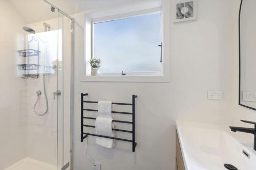 une salle de bain avec une douche et un lavabo et une fenêtre dans l'établissement Panoramic Farmhouse theme with shared spa pool, à Queenstown