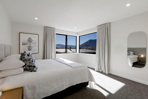 ein weißes Schlafzimmer mit einem großen Bett und einem großen Fenster in der Unterkunft A Surprise on Sunrise - luxury with sauna and spa in Queenstown