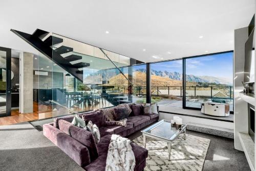 a living room with a purple couch and glass walls at St Marks Stunning Views Queenstown in Queenstown