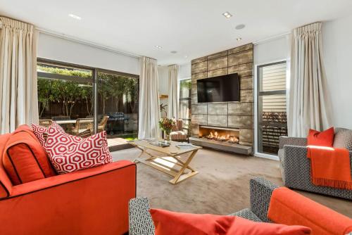 a living room with orange furniture and a fireplace at Central Queenstown 3 Bed Villa in Queenstown
