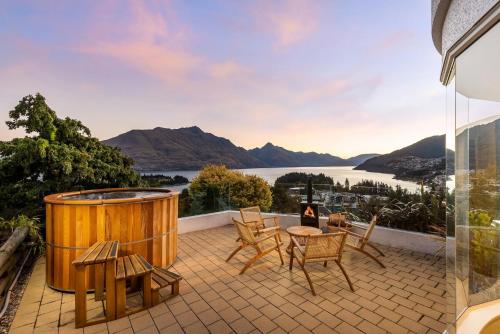 a hot tub on a patio with a view of a lake at Edinburgh 3BR 2BA with Hot Tub Views Fireplace in Queenstown
