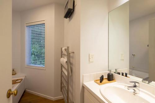 a white bathroom with a sink and a mirror at Edinburgh 3BR 2BA with Hot Tub Views Fireplace in Queenstown
