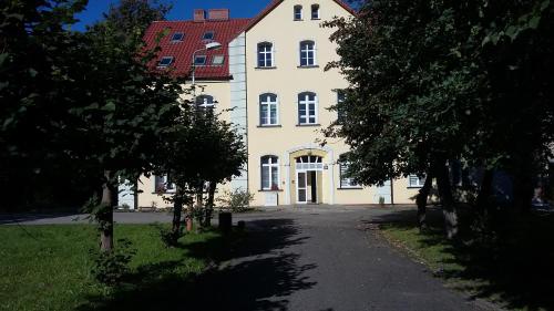 duży biały budynek z czerwonym dachem w obiekcie Apartament Parkowy w mieście Kętrzyn