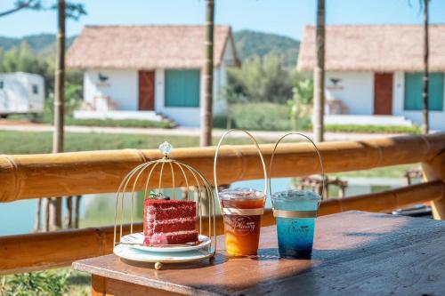 een tafel met een stukje taart en twee drankjes bij Plenary Khao Kho in Ban Nong Chaeng