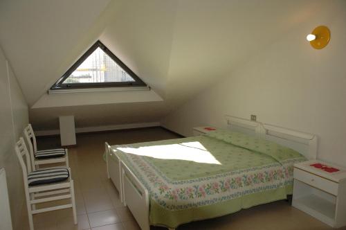 リニャーノ・サッビアドーロにあるAppartamento Arpaの小さな屋根裏のベッドルーム(ベッド1台、窓付)