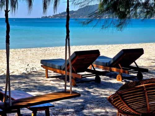 two chairs and a hammock on a beach at White Beach Hostel in Koh Rong Island