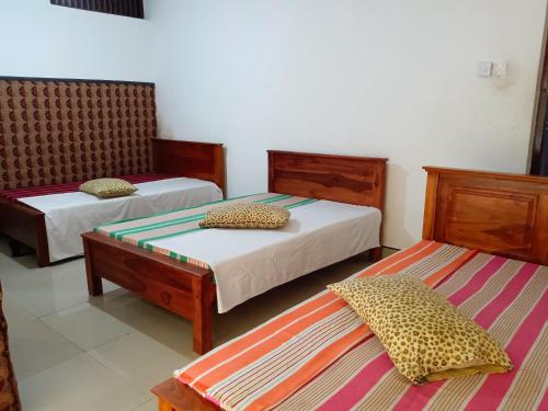 Habitación con 2 camas y 2 bancos. en NK Hotel and Restaurant, en Matale