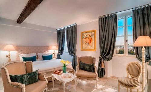 a hotel room with a bed and two chairs at Château Le Cagnard in Cagnes-sur-Mer