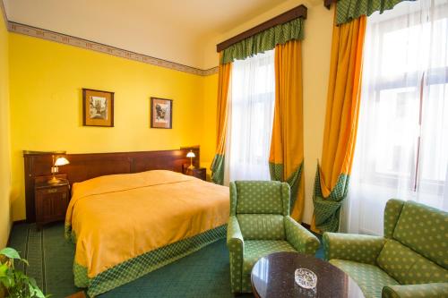 a bedroom with a bed and two chairs in it at Grandhotel Garni in Jihlava