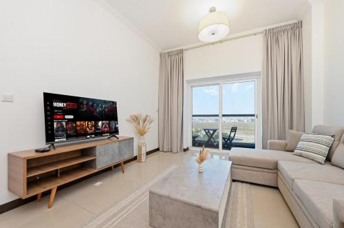 a living room with a couch and a flat screen tv at One Bedroom Apartment in the Heart of Dubai Silicon Oasis in Dubai