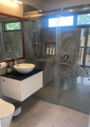a bathroom with a glass shower and a sink at Coffs Harbour Sanctuary in Coffs Harbour