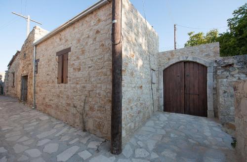 a brick building with a wooden door on a street at Oinoessa Traditional Boutique Guest Houses in Lofou