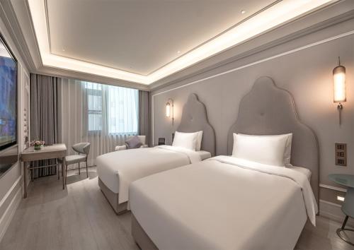 een hotelkamer met twee bedden en een televisie bij Mercure Anyang Downtown in Anyang