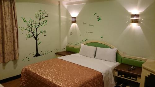 a bedroom with a bed with a tree painted on the wall at Rido Hotel in Taichung