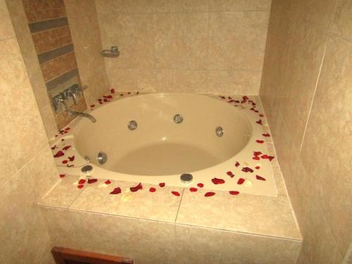 Hotel Waynapicchu في كوسكو: حوض استحمام مع بتلات ورد حمراء حوله