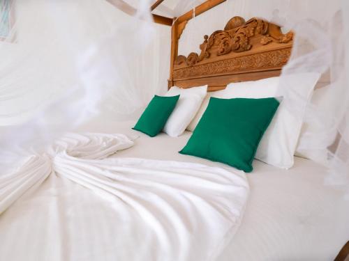 a bed with white sheets and green pillows at Florain Otium Talpe - 3 Bedroom Oceanfront Villa in Unawatuna