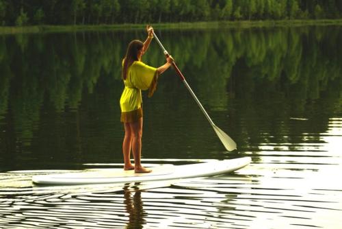 a woman standing on a paddle board in the water at namelis tyloje in Šarkiškės