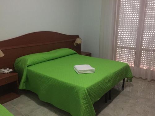 a green bed with a green blanket on top of it at Castelvetere Hotel in Caulonia