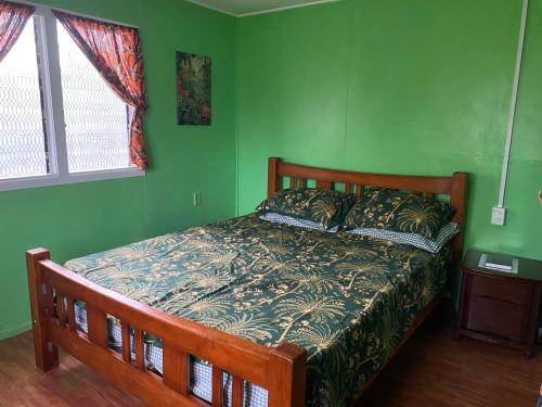 een slaapkamer met een bed met groene muren bij Mana ki he Mana Residence 