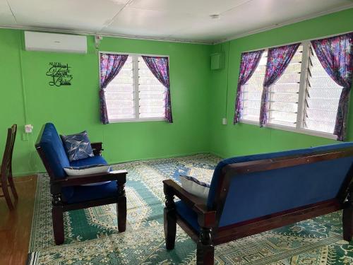 un soggiorno con 2 sedie e pareti verdi di Mana ki he Mana Residence 