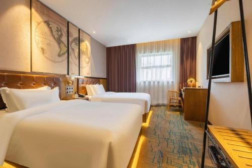 ein Hotelzimmer mit zwei Betten und einem Fernseher in der Unterkunft James Joyce Coffetel Tianjin Railway Station in Tianjin