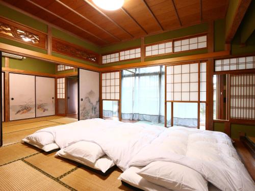 un grande letto bianco in una stanza con finestre di 旅館紀の国 