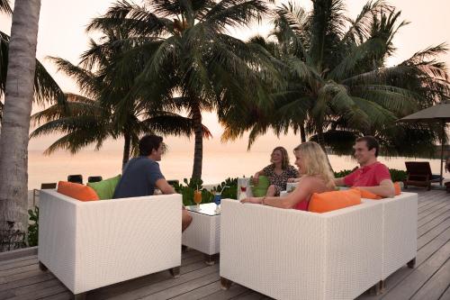 a group of people sitting at a table on the beach at Vilamendhoo Island Resort & Spa in Dhangethi