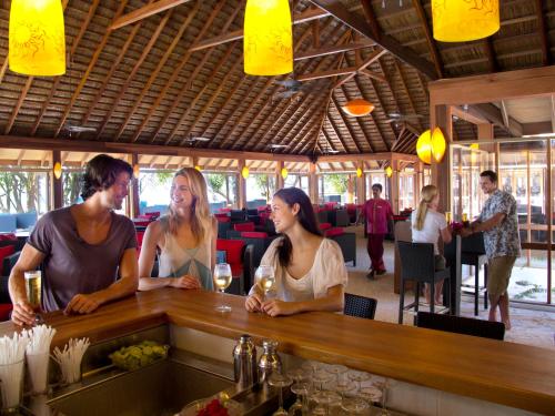 a group of people sitting at a bar in a restaurant at Vilamendhoo Island Resort & Spa in Dhangethi
