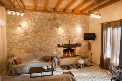 een woonkamer met een stenen muur en een open haard bij Τα πέτρινα στο Σκεπαστό in Kalavrita