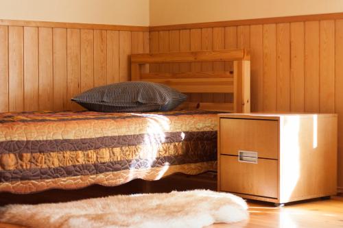 a bedroom with a bed and a wooden wall at Viesu nams Jaunzilakši in Vireši