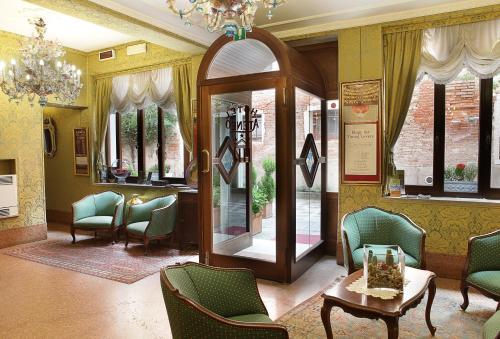 una sala de espera con sillas, mesa y espejo en Hotel Ateneo, en Venecia