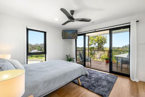 een slaapkamer met een bed en een plafondventilator bij The Grevilleas in Woombah