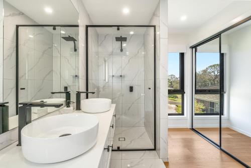 een witte badkamer met twee wastafels en een douche bij The Grevilleas in Woombah