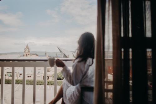 a woman sitting on a balcony looking out a window at Albany Motel & Apartments in Albany