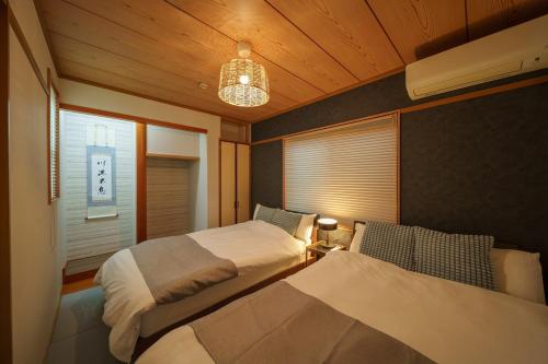 a bedroom with two beds and a lamp and a window at Triangle 2nd in Beppu