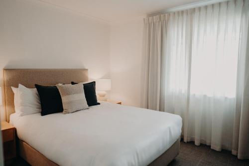 a bedroom with a large white bed and a window at Albany Motel & Apartments in Albany