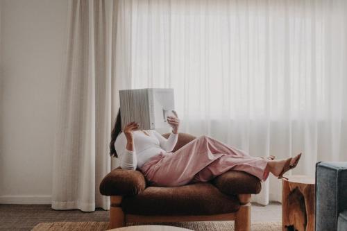 a woman laying in a chair reading a book at Albany Motel & Apartments in Albany