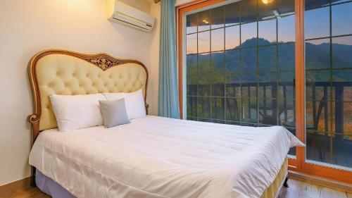 een bed in een kamer met een groot raam bij Gapyeong Elin Pension in Gapyeong