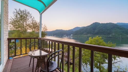 een balkon met een tafel en stoelen en uitzicht op een rivier bij Gapyeong Elin Pension in Gapyeong