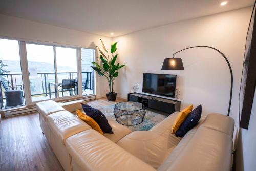 een woonkamer met een bank en een televisie bij 205 - Modern Suite - Pool and River View in Baie-Saint-Paul