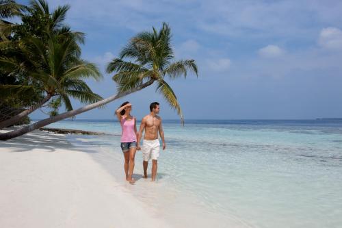 a man and a woman walking on a beach at Vilamendhoo Island Resort & Spa in Dhangethi