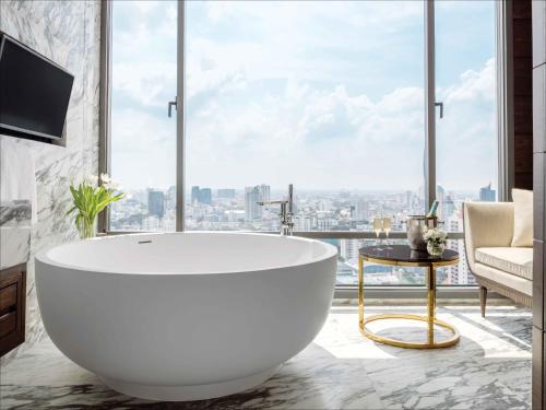 a bath tub in a bathroom with a large window at 137 Pillars Suites Bangkok in Bangkok