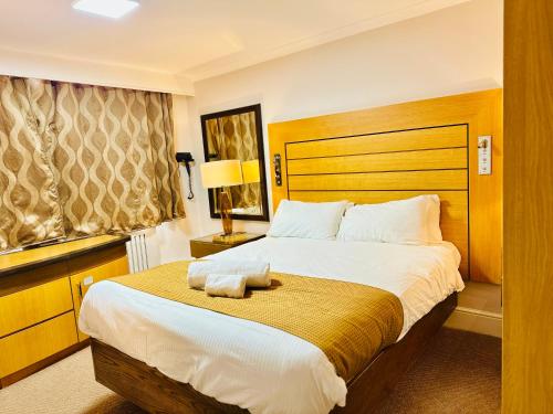 a bedroom with a large bed with a wooden headboard at Crown Hotel - Stone, Near Stoke-On-Trent by OYO in Stone