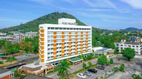 a hotel building with a mountain in the background at Phuket Merlin Hotel in Phuket