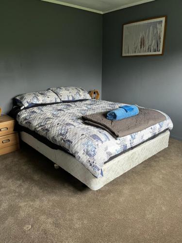 een slaapkamer met een bed met een blauw dekbed bij Rainbow Mountain cottage in Rotorua