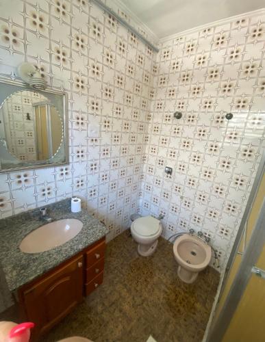a bathroom with a sink and a toilet and a mirror at Hostel San Pietro in Santos