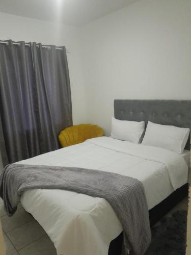 een slaapkamer met een groot bed met een grijze deken erop bij The Nexus Suites in Gaborone